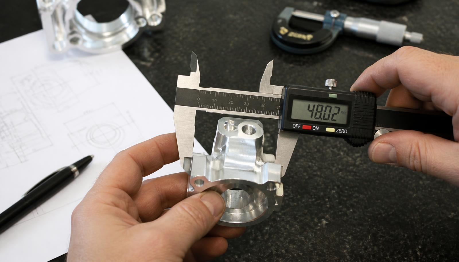 Machined aluminium component being measured with digital calipers
